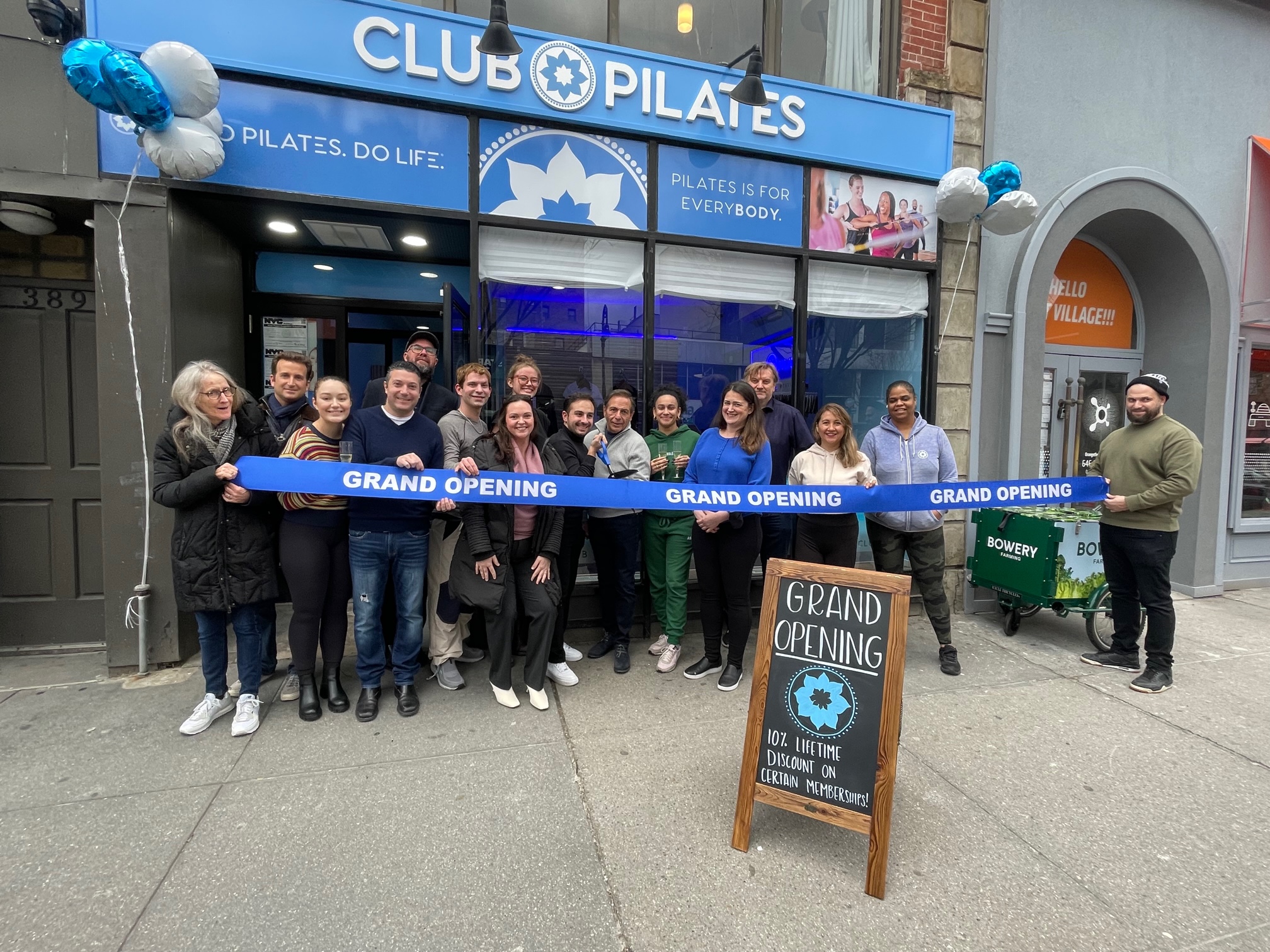 Ribbon cutting west village - photo of Club Pilates West Village Staff holding a ribbon of their grand opening in front of their store