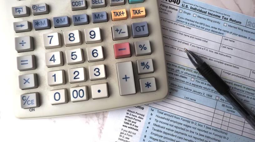 Photo of a calculator, a pen, and a 1040 tax form